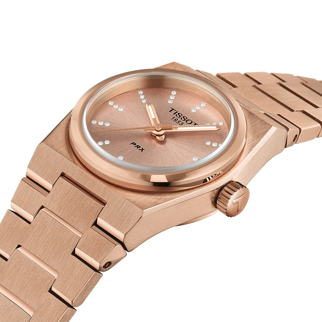 The Tissot PRX Quartz 25mm Watch by Tissot features a rose gold finish, stainless steel case, metallic bracelet, diamond hour markers on a minimalist dial, polished details, and a side crown engraved with the Tissot "T" logo.