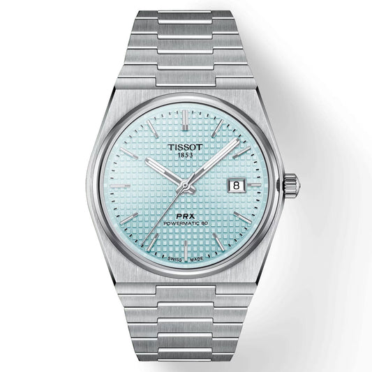 The Tissot PRX Powermatic 80 Automatic 40mm Watch is a silver wristwatch with a stainless steel case and a sleek stainless steel bracelet. It features a patterned light blue face with the words "TISSOT 1853" and "PRX Powermatic 80," includes an automatic movement, has scratch-resistant sapphire crystal, and offers a date window at the 3 o'clock position.