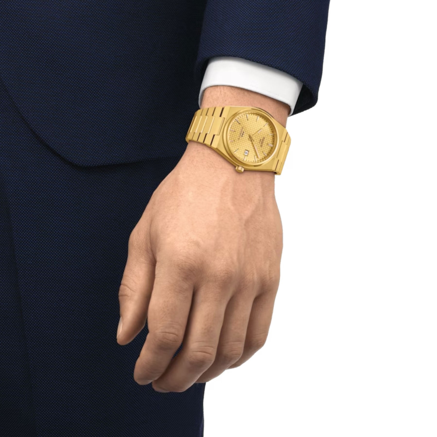 A person dressed in a dark blue suit and white shirt showcases a Tissot PRX Powermatic 80 Automatic 40mm Watch on their wrist. The close-up emphasizes the elegance of the Tissot watch with automatic movement, along with the shirt cuff peeking out from under the suit sleeve.