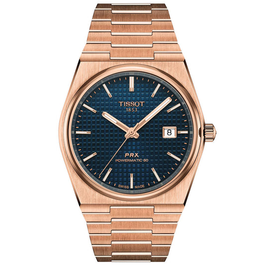 The Tissot PRX Powermatic 80 Automatic 40mm Watch features a rose gold case, blue textured dial, gold hour markers, date window at 3 o’clock, and a metal link bracelet for a sleek, modern look.