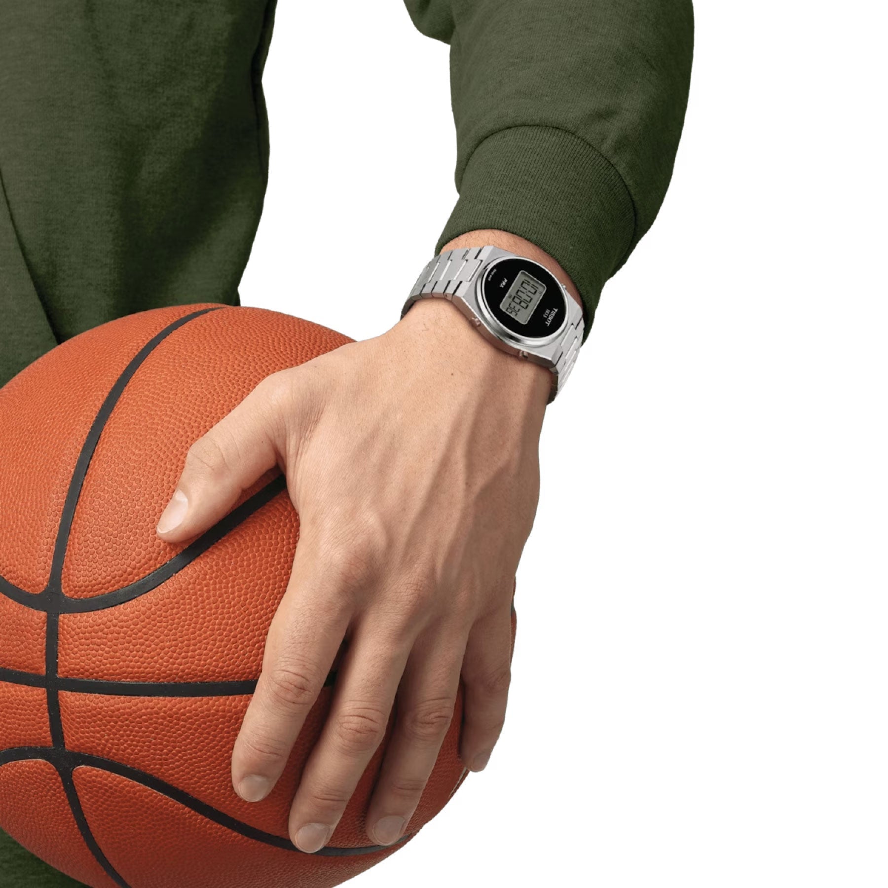 A person in a green sweatshirt holds a basketball, showcasing the stylish Tissot PRX Digital Quartz 40mm Watch prominently displayed on their left wrist with a silver strap. The watch, from the esteemed brand Tissot, features dual time zones and has time and date details clearly visible against the plain white background.