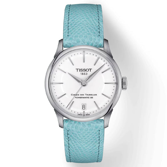 The Tissot Chemin Des Tourelles Powermatic 80 Automatic 34mm Watch features a white dial with silver casing, complemented by silver hour markers and hands. It includes a date window at the 6 o'clock position and showcases "Chemin Des Tourelles Powermatic 80" on the face. This watch is equipped with a textured light blue strap and is driven by the Swiss automatic Powermatic 80 movement.