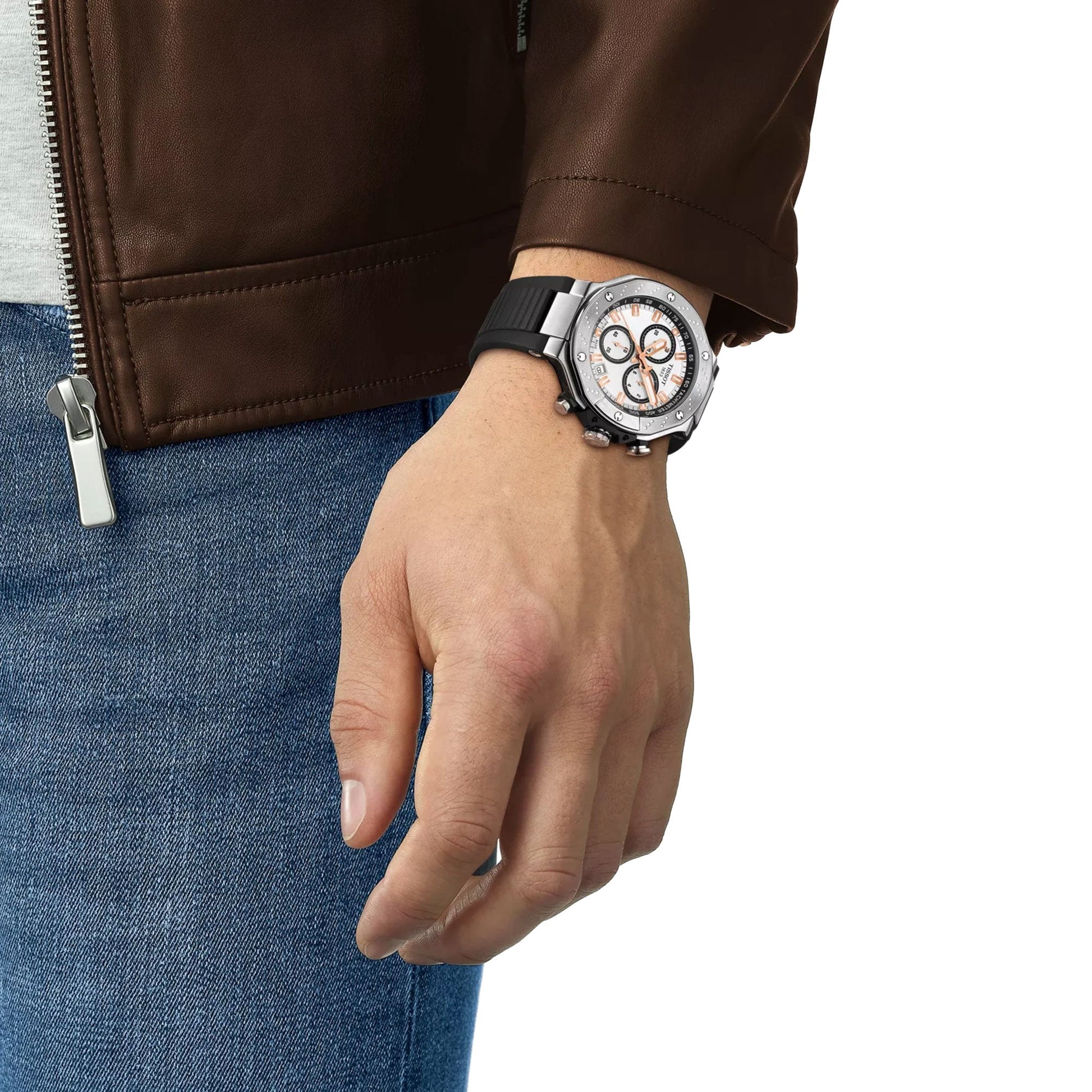 Wearing a brown jacket and blue jeans, a person shows off a bold Tissot T-Race Chronograph Quartz 45mm watch featuring a silver analog face and black strap on their left wrist.