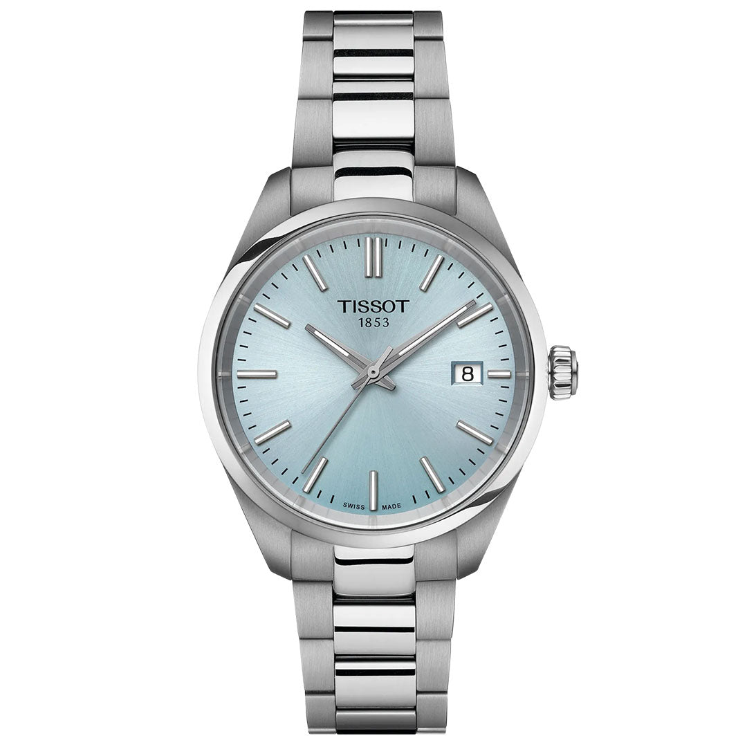 The Tissot PR100 Quartz 34mm Watch has a 316L stainless steel band, light blue dial, silver markers and hands, a date window at 3 o’clock, and "TISSOT 1853" below 12.