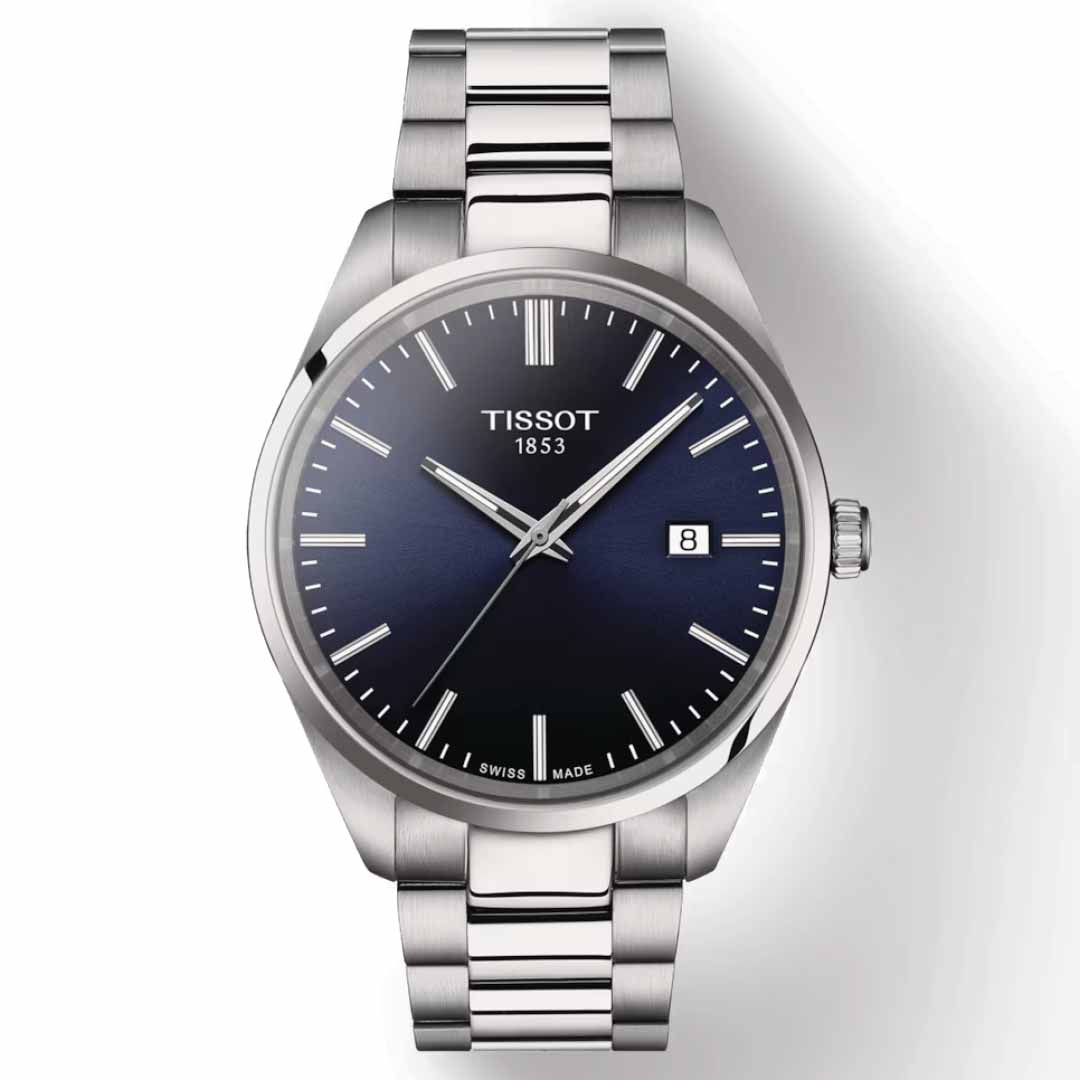 The Tissot PR100 Quartz 40mm Watch, crafted by Tissot, showcases a sleek silver finish and a sophisticated dark blue dial. It is equipped with Swiss Quartz movement and features a date window at the 3 o'clock position. The watch is designed with scratch-resistant sapphire crystal and adorned with silver hour markers and hands. Its 316L stainless steel bracelet enhances durability, while the dial proudly displays "Tissot 1853.