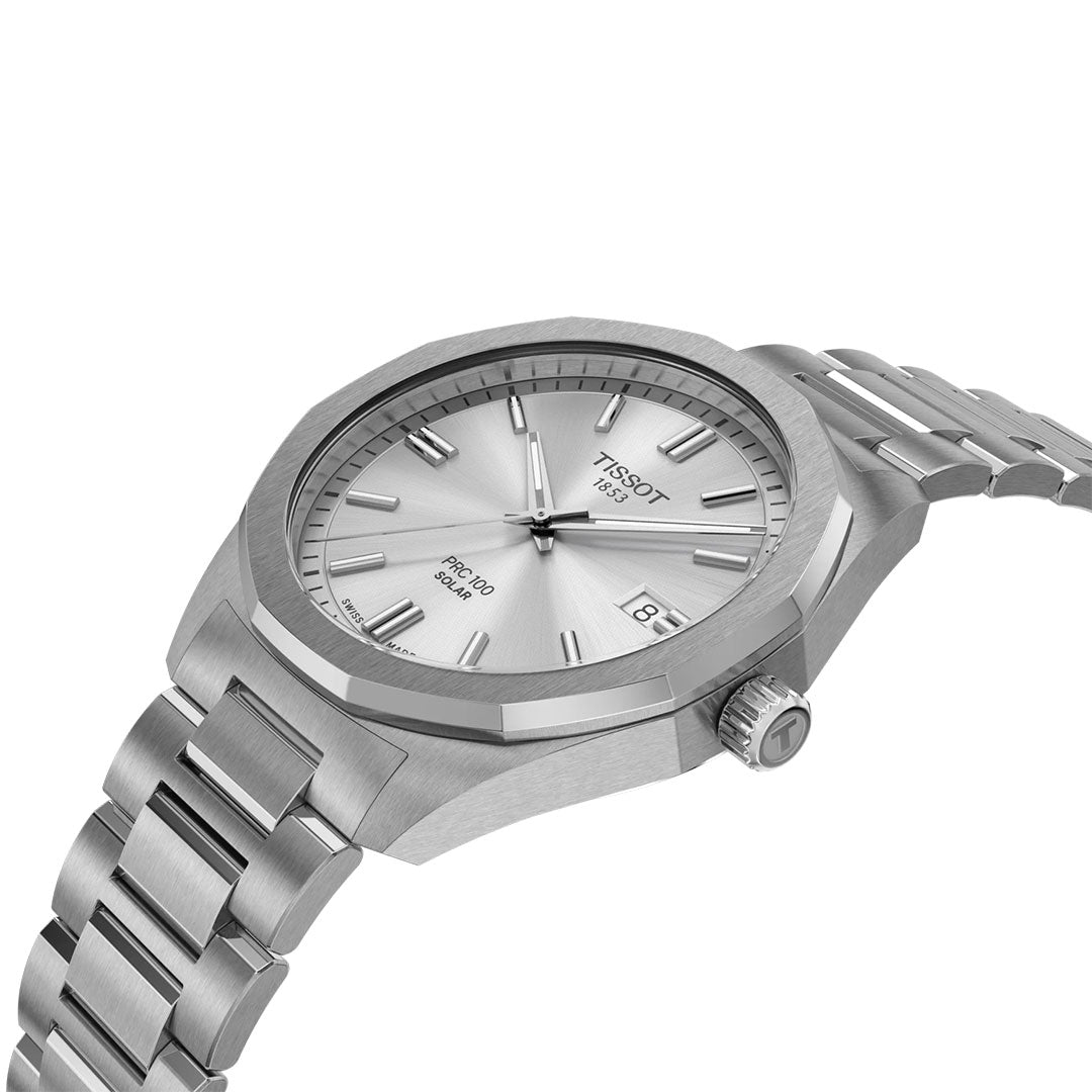 A Tissot PRC 100 Solar Quartz 39mm watch with a silver tone, metal band, silver dial, minimalist markers, date at 3 o’clock, and textured bezel is displayed at an angle on a white background.
