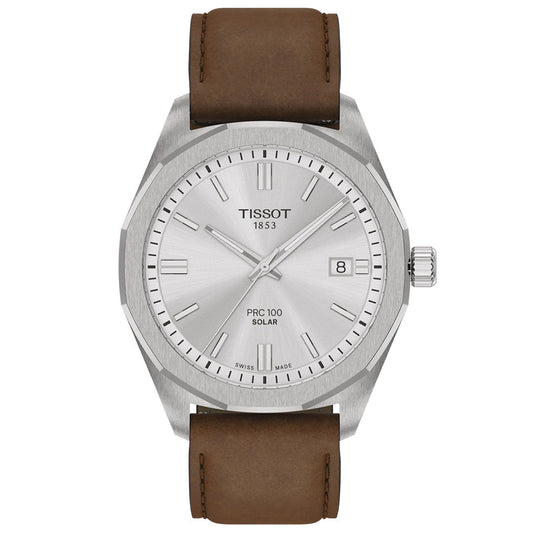 The Tissot PRC 100 Solar Quartz 39mm Watch features a silver dial, silver hour markers, date display at 3 o'clock, brown leather strap, solar-powered movement, minimalistic design, and displays the Tissot 1853 logo.
