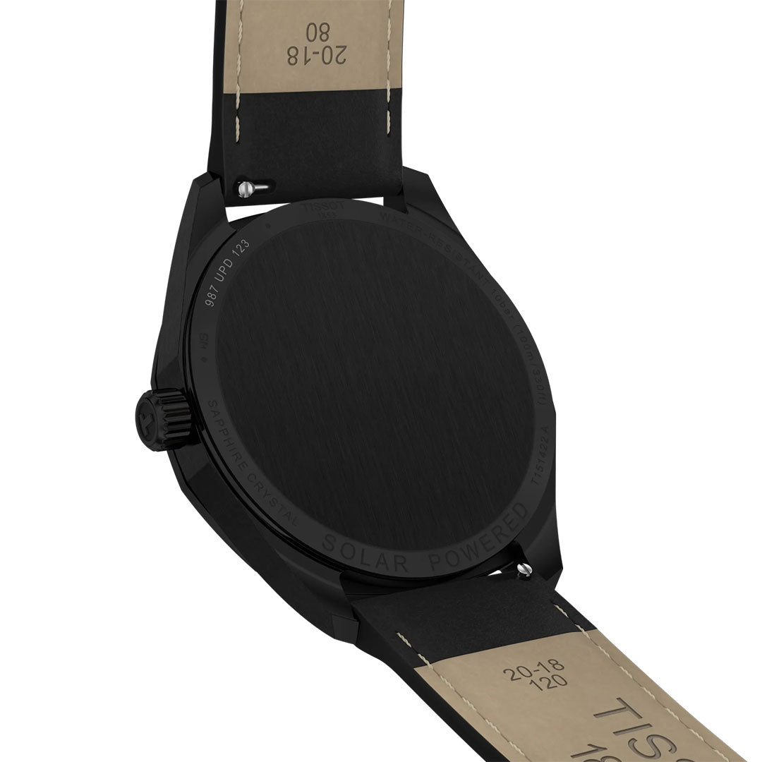 A close-up of the back of a black Tissot PRC 100 Solar Quartz 39mm watch with a tan leather strap. “SOLAR POWERED” and other details are engraved around the case back of this Tissot timepiece.