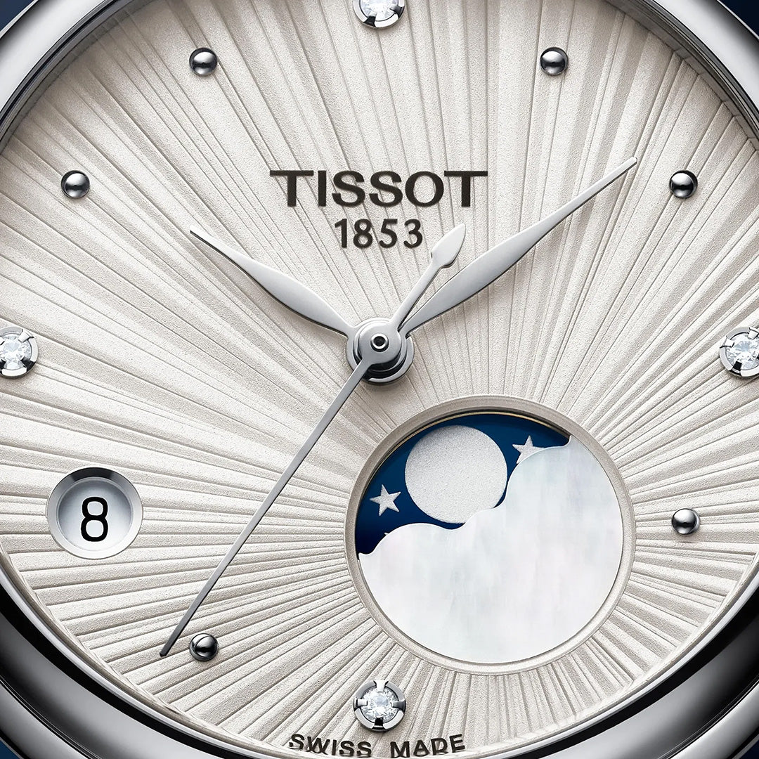 Close-up of the Tissot Desir Moonphase Quartz 29.6mm watch face, showcasing a sunburst-patterned dial with silver hands, diamond hour markers, a date window at 8 o’clock, and a moonphase display above 6 o’clock. The quartz movement timepiece features “Tissot 1853” at the center of the dial.