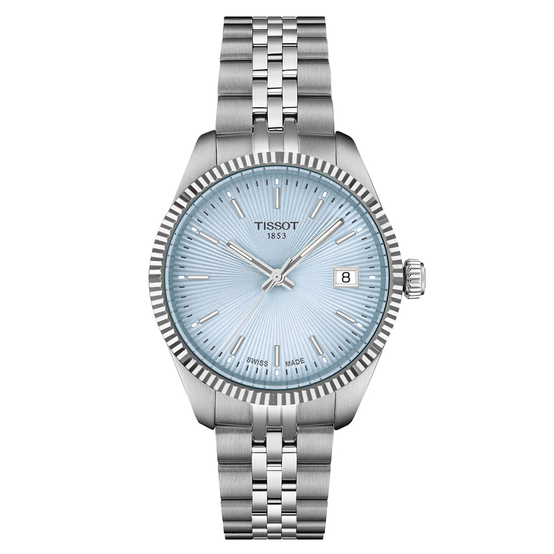 The Tissot Ballade Quartz 34mm Watch is a silver Tissot wristwatch featuring a light blue guilloché dial with silver hour markers, hands, and a date display at 3 o'clock. It includes a stainless steel bracelet and fluted bezel for added elegance.