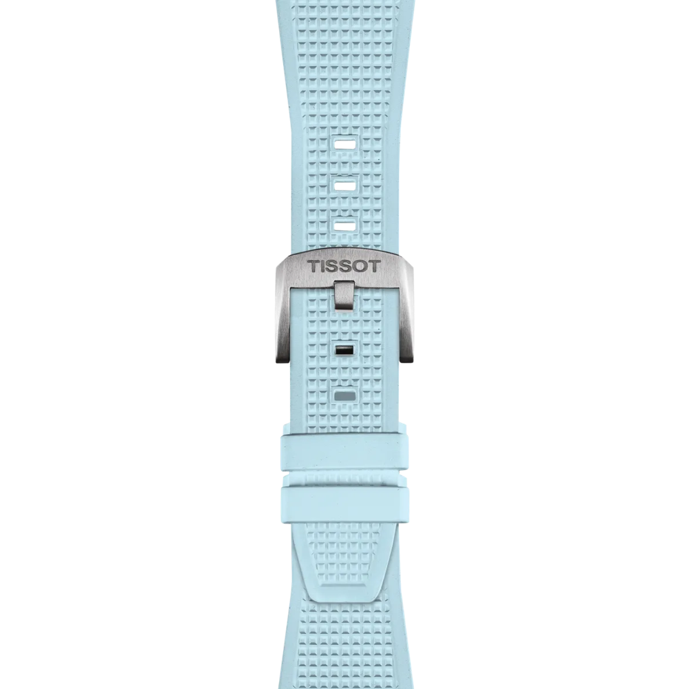 The Tissot Official PRX Light Blue Rubber Strap features a textured light blue silicone design, complete with a silver metal buckle engraved with the Tissot brand name. The strap includes rectangular adjustment holes and two loops to securely hold the strap end in place.
