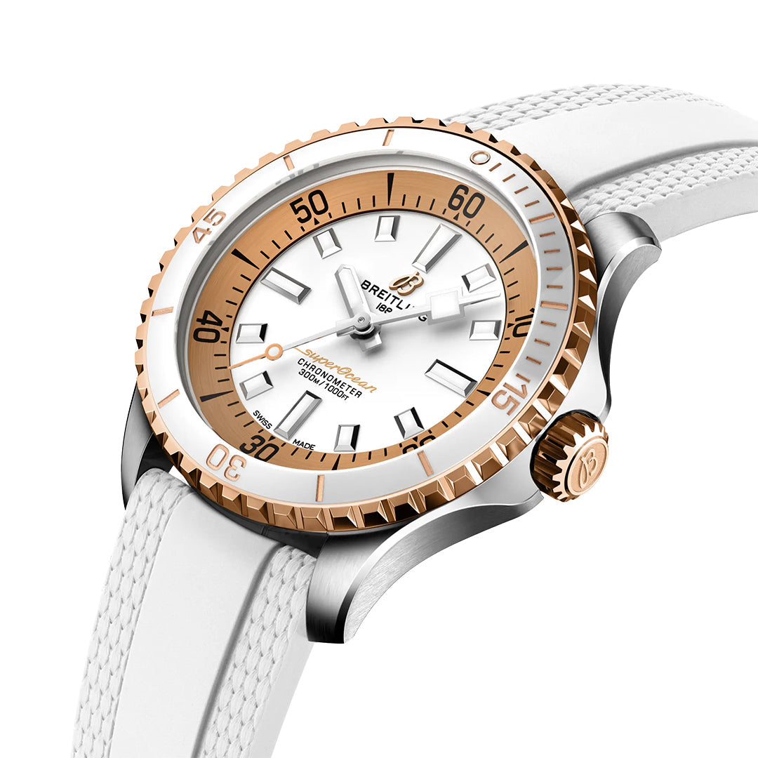 The BREITLING Superocean Automatic 36 features a white face, gold and silver bezel, white strap, gold accents, bold hour markers, a rotating bezel with minute markings, and displays the Breitling brand.