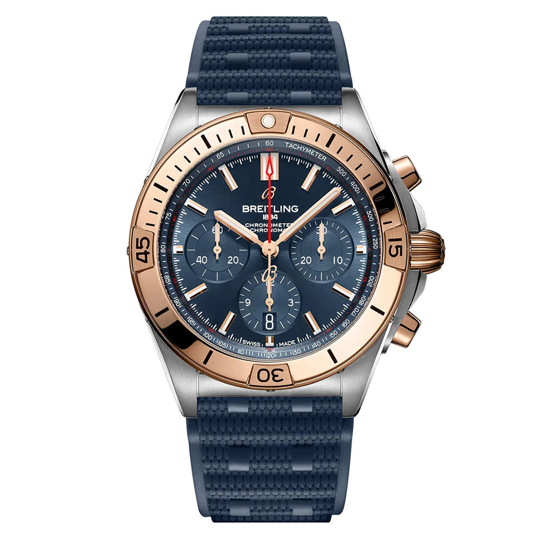 The BREITLING Chronomat B01 42 is a luxury wristwatch by Breitling, featuring a blue dial with rose gold accents on the bezel and crown, inspired by aviation design. It includes chronograph subdials, a date display, and has hands and hour markers that are luminous. The watch comes with a blue textured rubber strap.