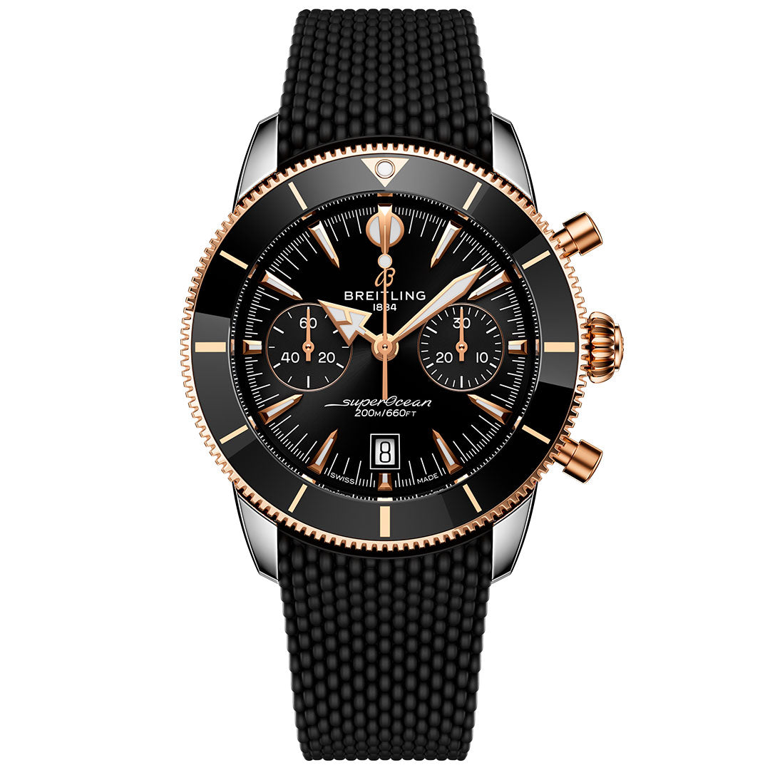 The Breitling Superocean Heritage B01 Chronograph 42 features a black dial with gold accents, three subdials, a date window at 6 o'clock, and a textured black strap for luxurious dive-ready style.
