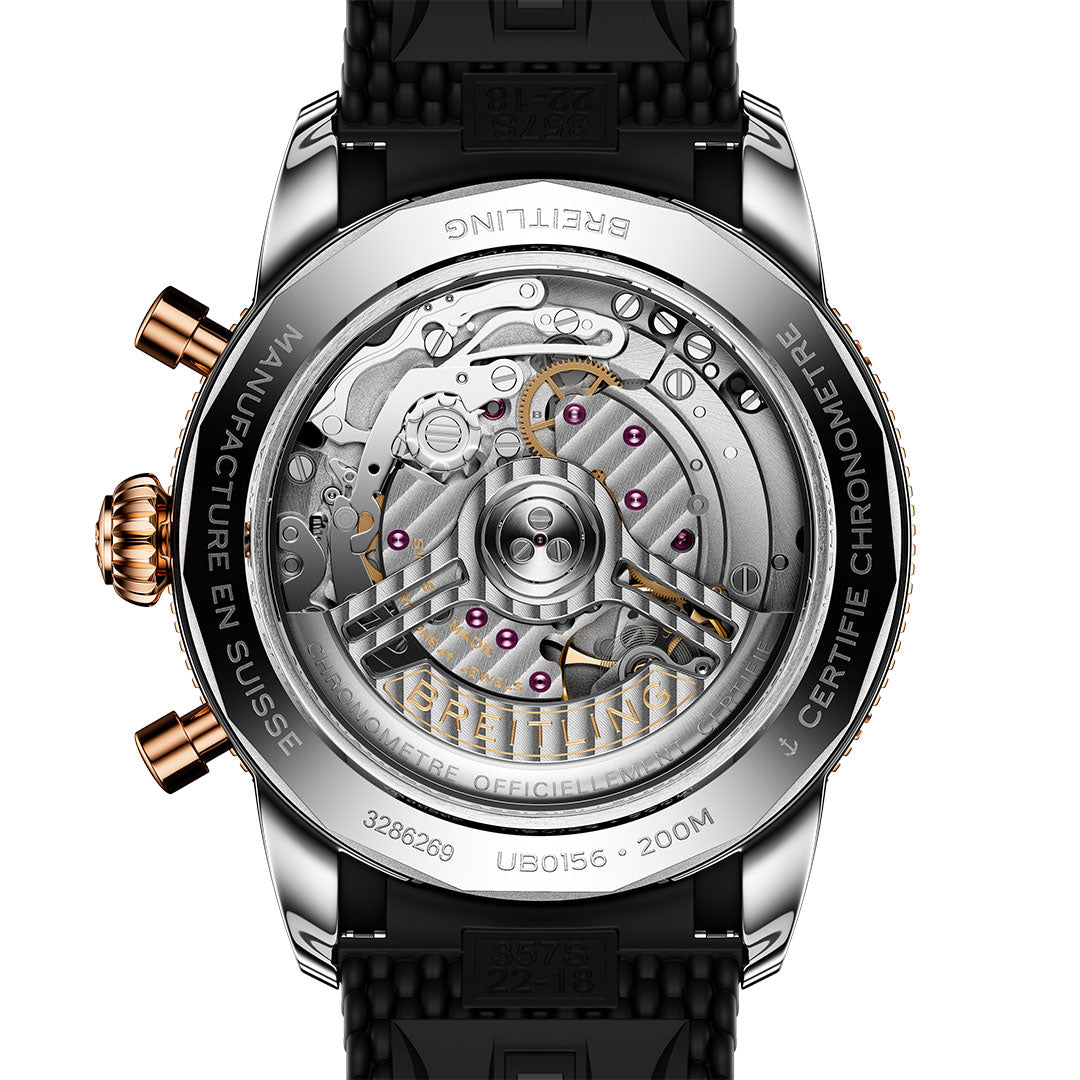 The BREITLING Superocean Heritage B01 Chronograph 42 showcases its Breitling Manufacture Caliber 01 through a transparent case back, engraved rim text, and features a black textured strap.