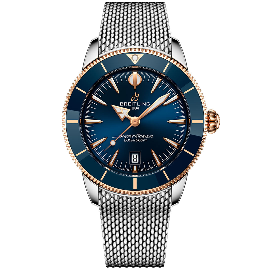 The BREITLING Superocean Heritage B31 Automatic 44 features a blue dial, gold bezel and crown, date window at 6 o’clock, stainless steel mesh bracelet, and offers 200m/660ft water resistance.