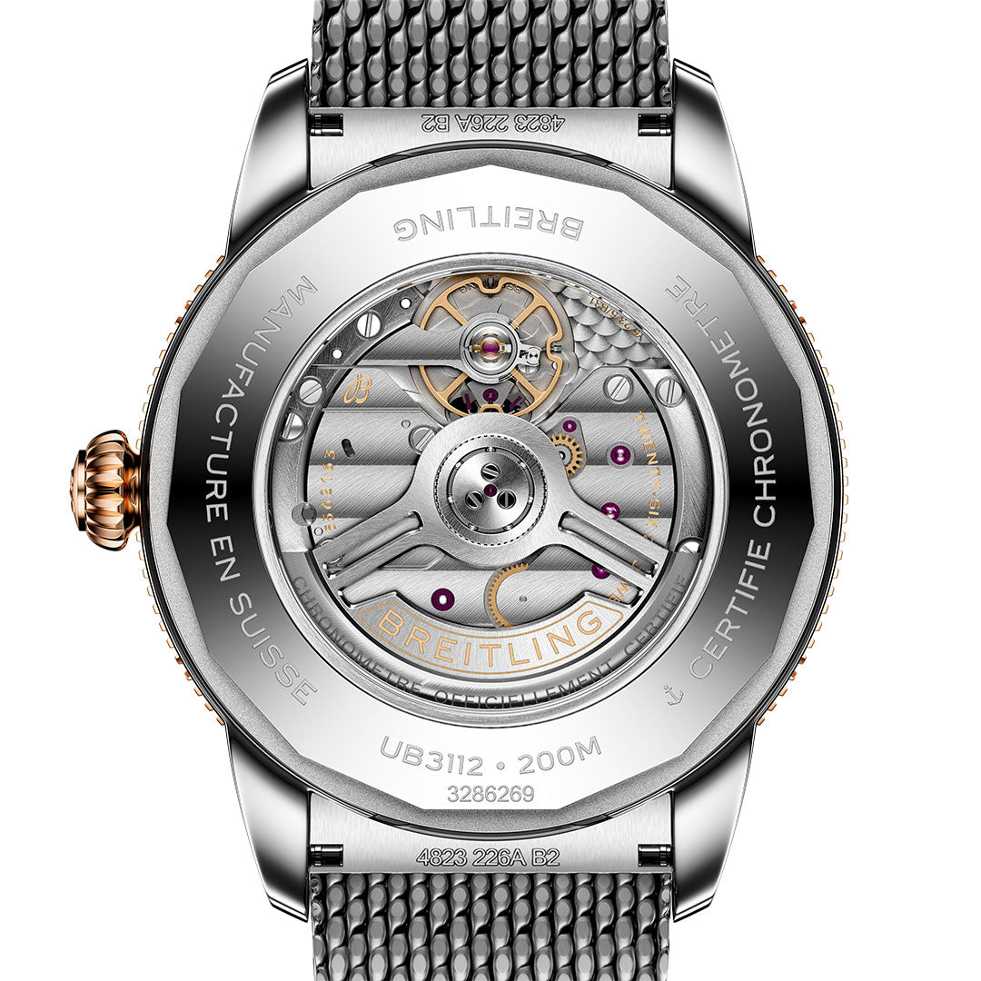 Close-up of the back of a Breitling Superocean Heritage B31 Automatic 44, showing its detailed mechanical movement through a transparent case back with engraved text and a metal mesh strap.