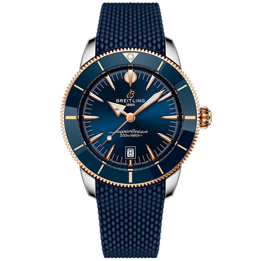 The Breitling Superocean Heritage B31 Automatic 44 is a luxury dive watch featuring a blue textured strap, blue dial and bezel with gold accents, automatic movement, date at 6 o’clock, and 200m/660ft water resistance.