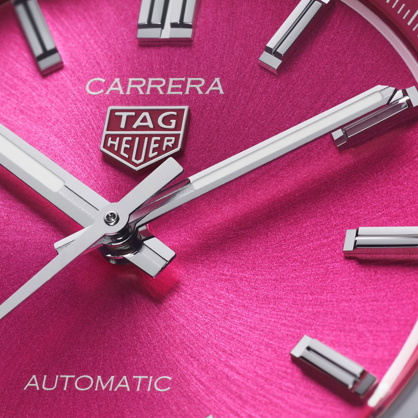 Close-up of a TAG Heuer Carrera Date Automatic 36mm watch in steel, featuring a vibrant pink dial with silver hands and hour markers. The face displays the TAG Heuer logo along with the inscriptions “Carrera” and “Automatic.”.