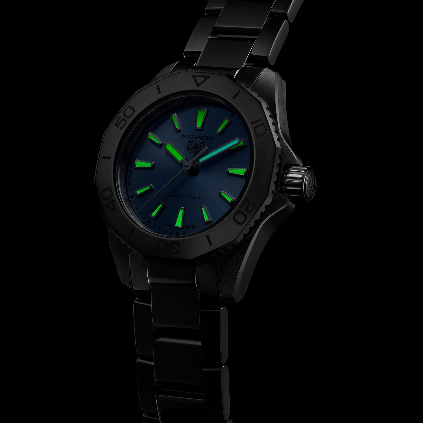 A TAG Heuer Aquaracer Professional 200 Quartz 30mm women’s watch in black, featuring glowing green hour markers and hands that display striking luminescence against the dark dial in low light.