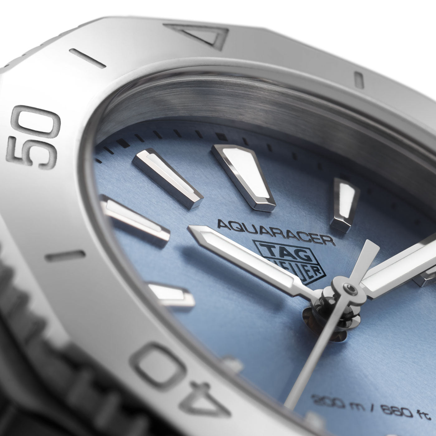 Close-up of a TAG Heuer Aquaracer Professional 200 Quartz 30mm watch face, featuring a blue dial, silver hour markers, and white hands. The bezel displays minute markers, and the TAG Heuer logo is visible on the dial.