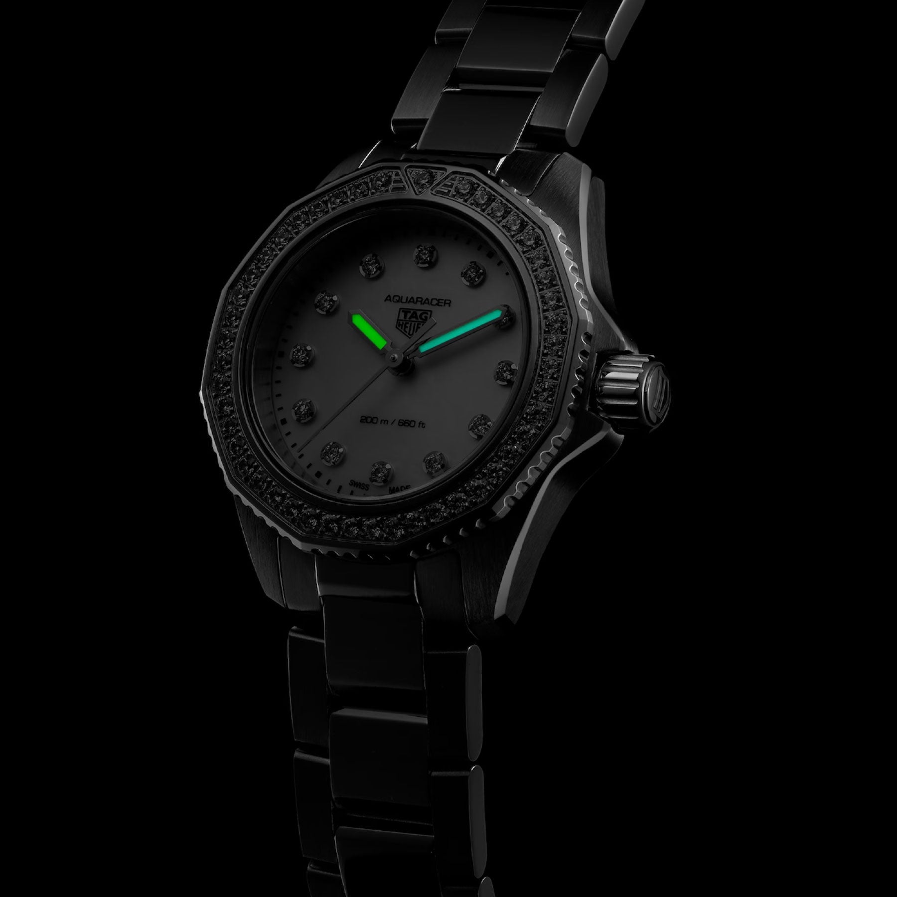 The TAG Heuer Aquaracer Professional 200 Quartz 30mm Watch by TAG Heuer is displayed on a black metal band against a black background. This elegant timepiece features a sleek black face with diamond hour markers and luminous green hour and minute hands, housed in a durable 30mm steel case and powered by precise quartz movement for dependable performance.