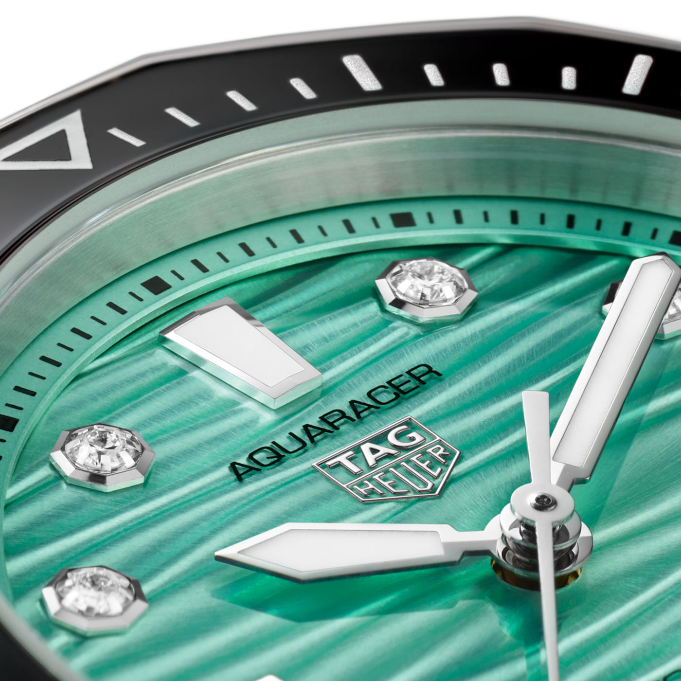 Close-up of the TAG Heuer Aquaracer Professional 300 Date Automatic 36mm Watch by TAG Heuer, showcasing its turquoise textured dial with geometric gem-set hour markers and bold silver hands, all framed by a striking black and silver bezel. This elegant timepiece perfectly blends luxury with professional performance.