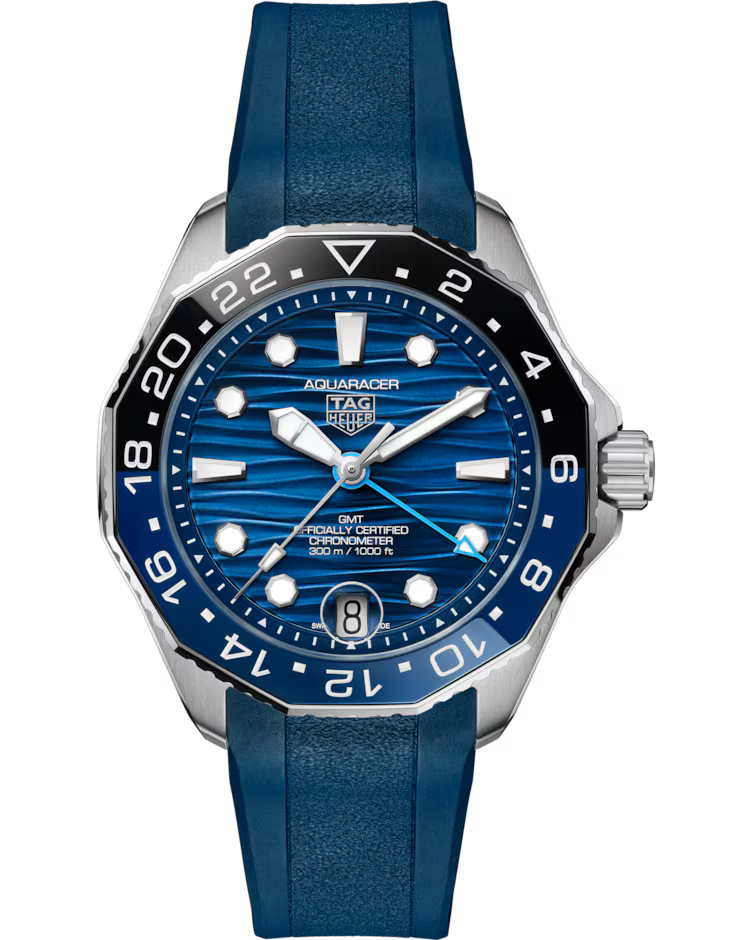 The TAG Heuer Aquaracer Professional 300 GMT Automatic 42mm Watch features a striped blue dial with silver hour markers, a date window at 6 o’clock, and a blue rubber strap. Its bezel is black and blue with white numerals.