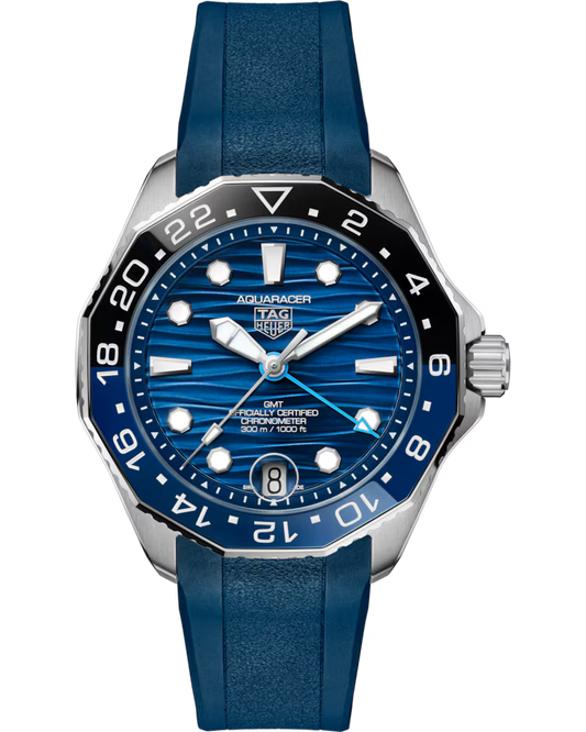 The TAG Heuer Aquaracer Professional 300 GMT Automatic 42mm Watch features a striped blue dial with silver hour markers, a date window at 6 o’clock, and a blue rubber strap. Its bezel is black and blue with white numerals.