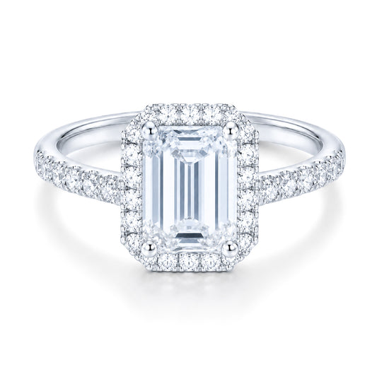 The Raffi&Co.® 14K White Gold Emerald Halo Diamond Engagement Ring features a large emerald-cut center diamond, a halo of round diamonds, and additional diamonds on the band.