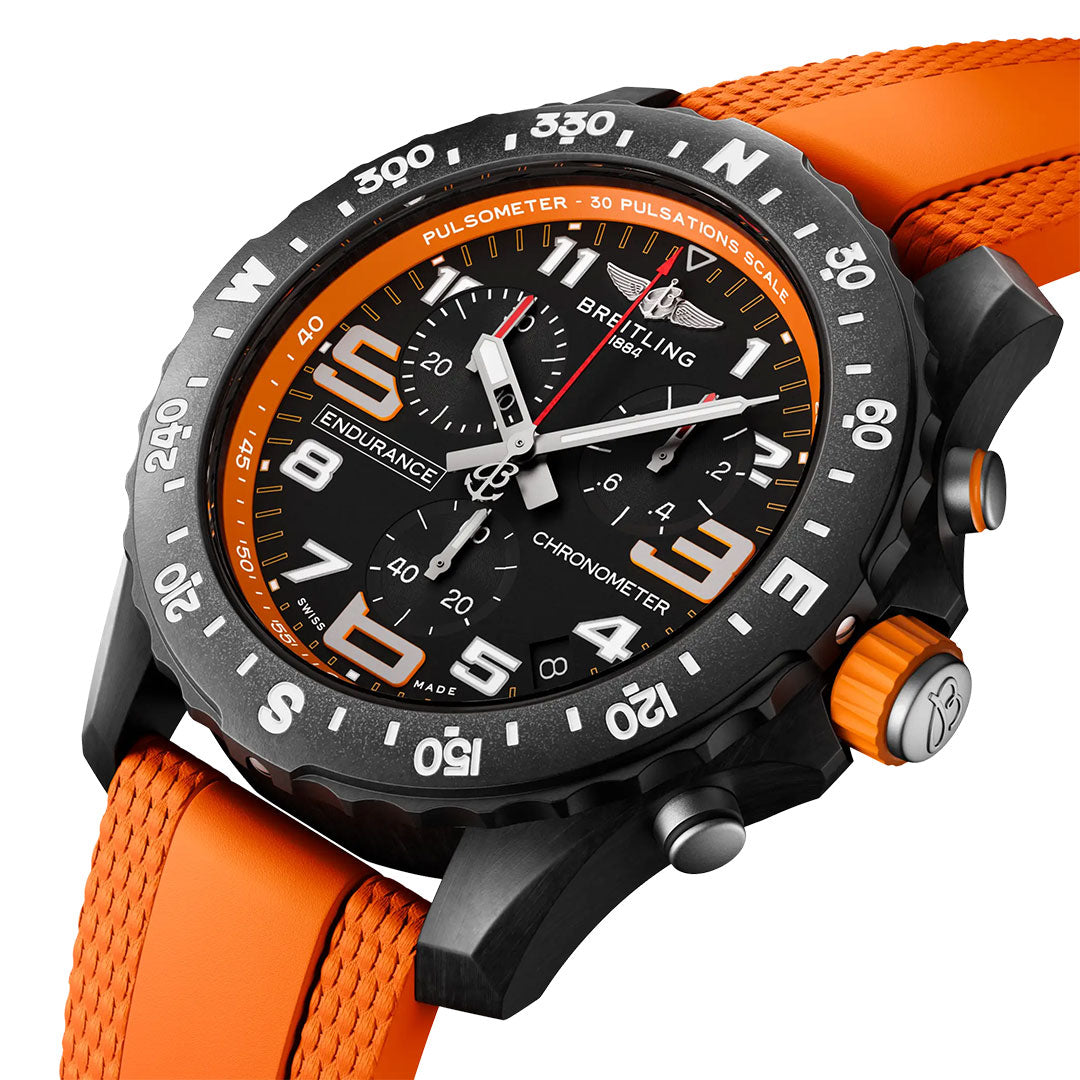 A close-up of the Breitling Professional Endurance Pro 44 chronograph features a bold orange rubber strap, large white numerals, and orange accents on the bezel and buttons, with a detailed multi-dial watch face.