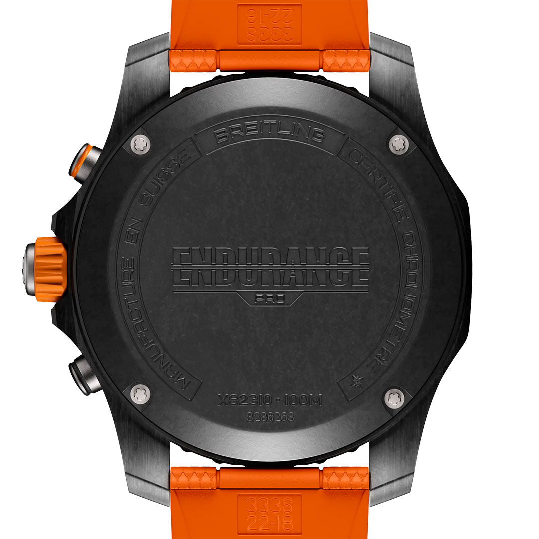 Back of a Breitling Professional Endurance Pro 44 watch with orange strap. The black case is engraved with “ENDURANCE,” “MANUFACTURE EN SUISSE,” “100M,” and “BREITLING CHRONOMETRE.”.