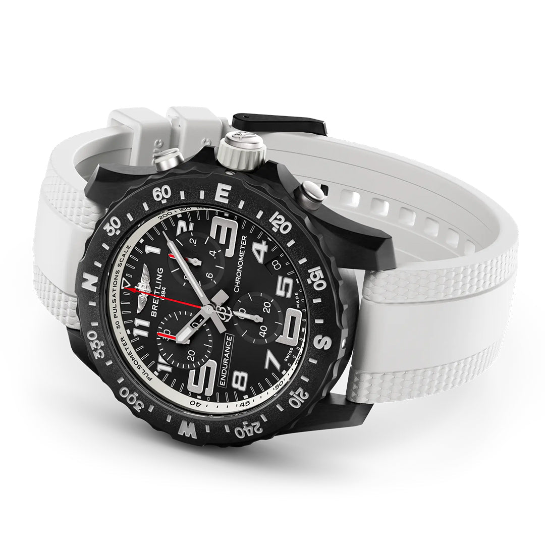 The Breitling Endurance Pro 44 is a black and silver athleisure watch with a white textured rubber strap, bold black bezel, three subdials, and a lightweight Breitlight® case, shown on a white surface.