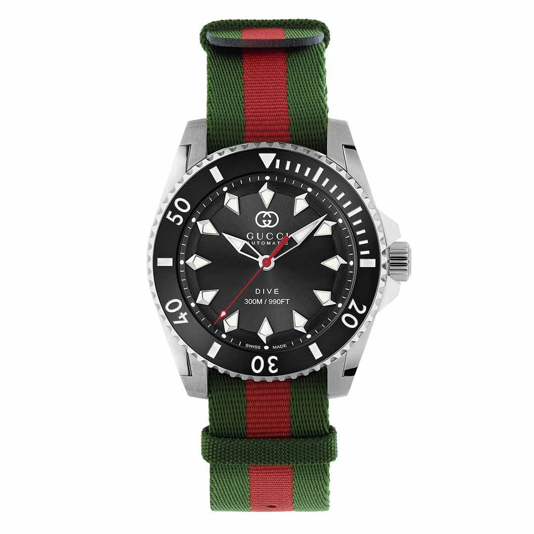 Introducing the Gucci Dive Automatic 40mm Watch, a luxury timepiece from GUCCI featuring an automatic movement and a sleek silver case. Its black dial with bold white markers pairs perfectly with the unidirectional bezel. The iconic Interlocking G logo is beautifully displayed on its green and red striped fabric strap.