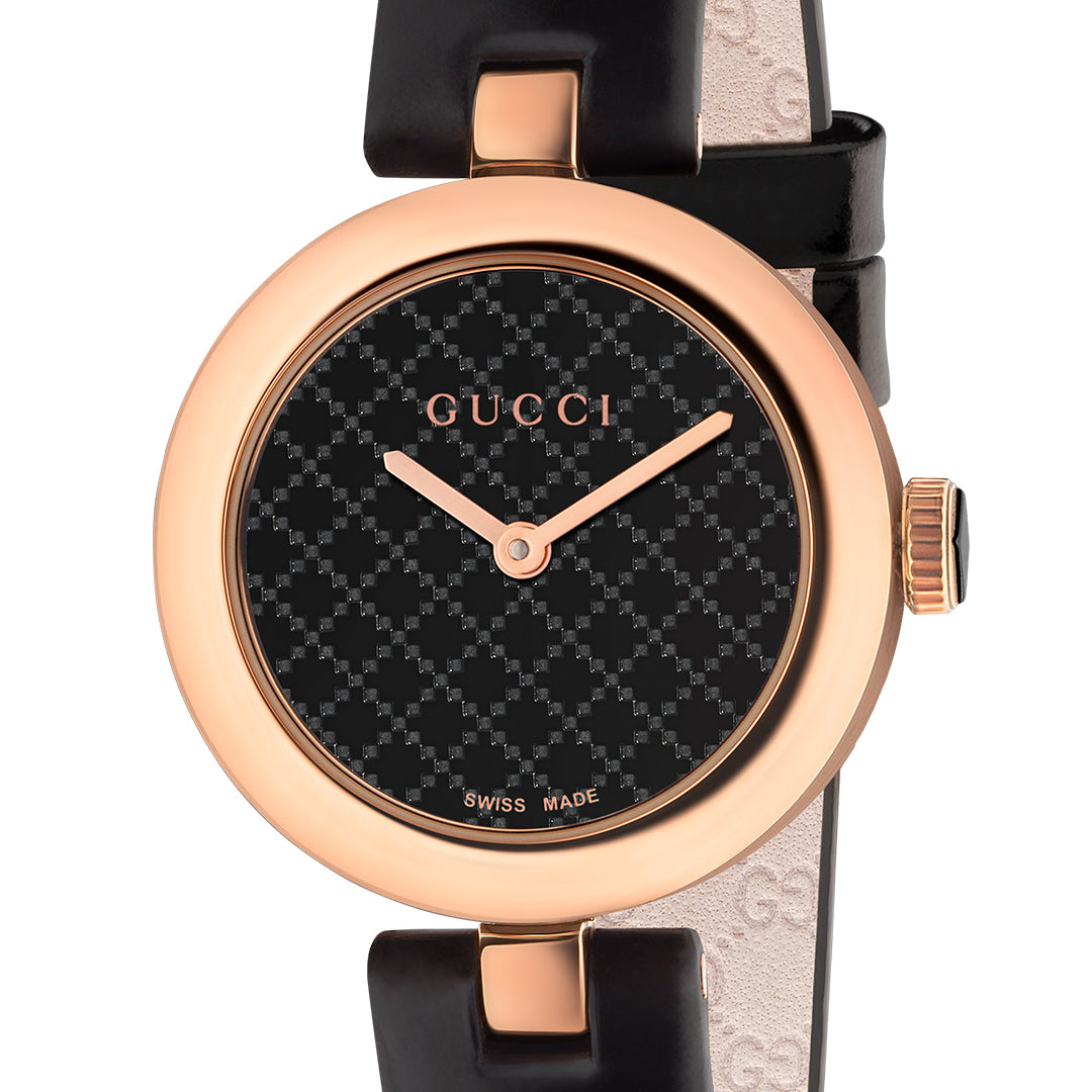 The Gucci Diamantissima Quartz 27mm Watch by GUCCI is an elegant timepiece with a black leather strap and a rose gold case. It features a round face displaying a black checkered pattern, highlighted by rose gold hands and indices, with the iconic "Gucci" logo at the top and "Swiss Made" at the bottom.