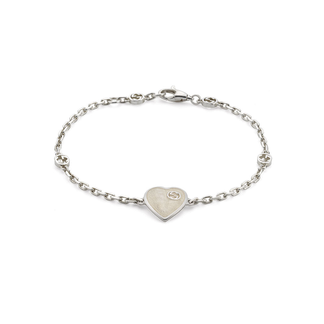 The Gucci Interlocking G Heart Enamel Sterling Silver Bracelet by GUCCI Fine Jewellery features a heart charm and circular accents on a sterling silver chain with a lobster clasp.