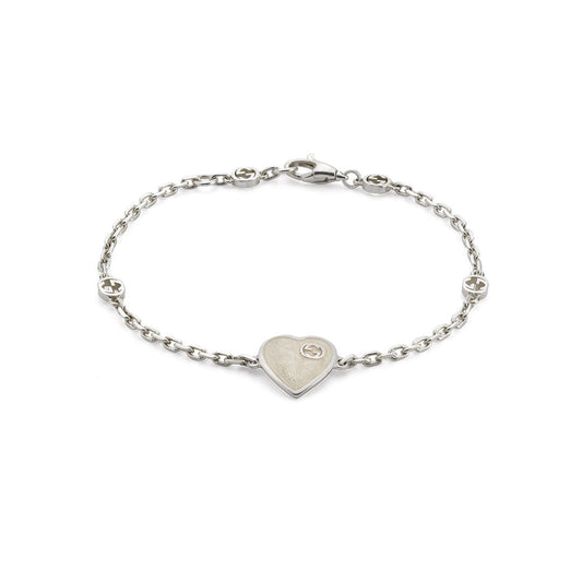 The Gucci Interlocking G Heart Enamel Sterling Silver Bracelet by GUCCI Fine Jewellery features a heart charm and circular accents on a sterling silver chain with a lobster clasp.