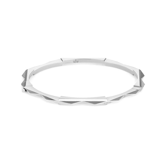 The Gucci Link to Love 18K White Gold Studded Bangle from GUCCI Fine Jewellery features a sleek geometric design with a smooth finish and subtle engravings. Its thin, angular facets deliver a modern, minimalist aesthetic, reminiscent of high-end Gucci elegance.