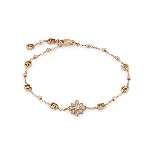 The Gucci Flora 18K Rosé Gold Diamond Charm Bracelet by GUCCI Fine Jewellery showcases a graceful design with small linked circles and a central flower adorned with sparkling stones. It features an adjustable clasp closure to ensure a perfect fit.