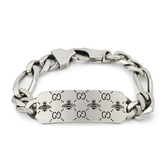 The Gucci GG and Bee Engraved Sterling Silver Bracelet by GUCCI Fine Jewellery is elegantly crafted with a rectangular plate highlighted by engraved bees and GG motifs. Its contemporary, fashionable design is finished with a fold-over clasp to ensure secure wear.