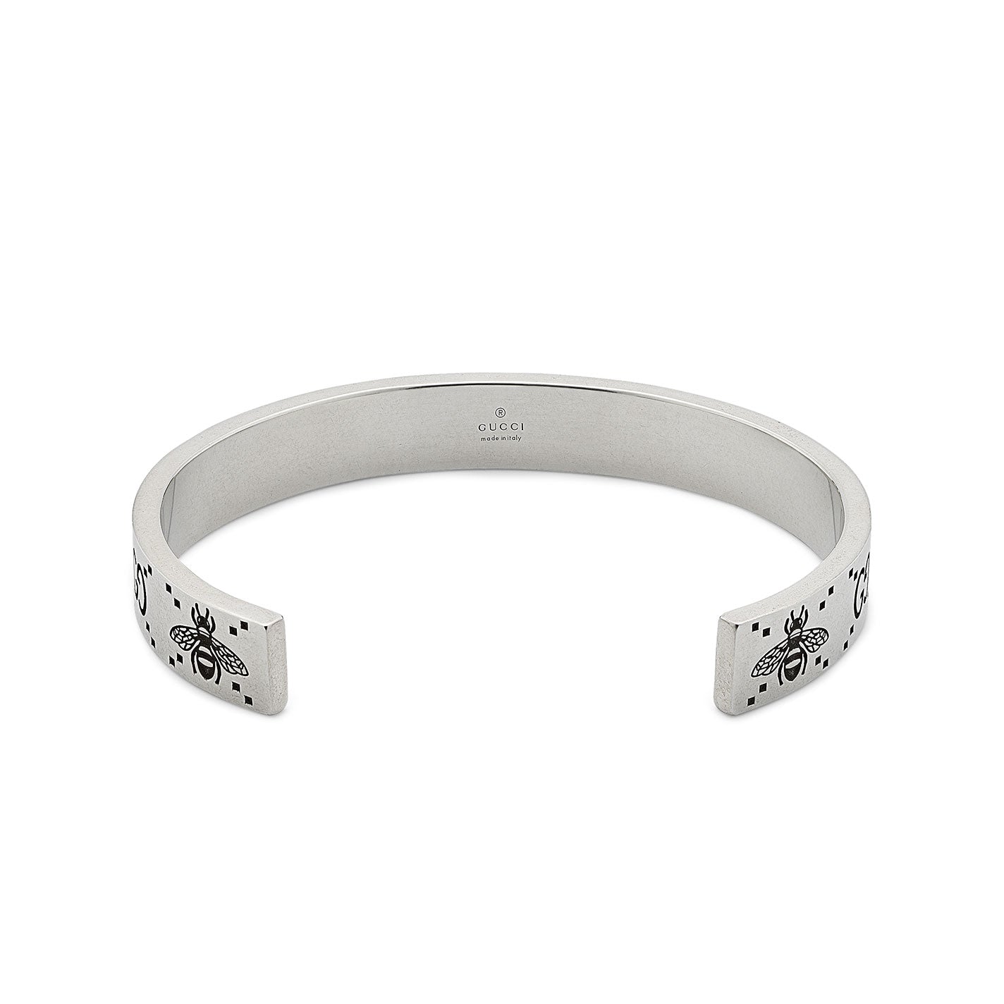 The Gucci GG And Bee Engraved Sterling Silver Cuff Bracelet by GUCCI Fine Jewellery showcases bee and star engravings with a subtle brand name inscription on the inner side. Its open-ended design, highlighted by a refined GG motif, adds a modern touch to this elegantly crafted accessory.