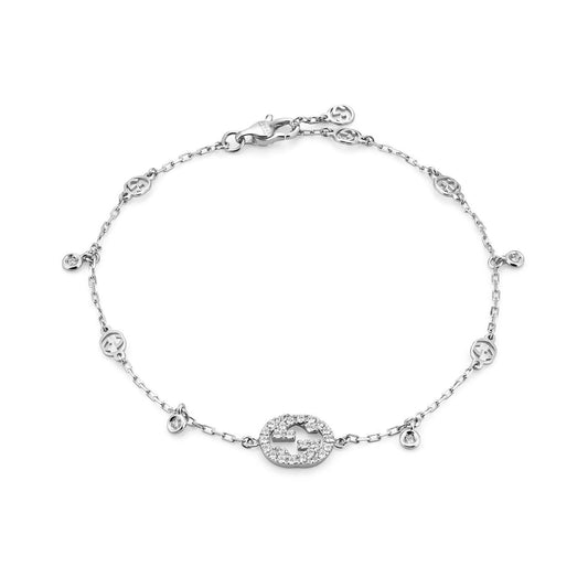 Presenting the Gucci Interlocking G 18K White Gold Diamond Bracelet from GUCCI Fine Jewellery: a sophisticated silver chain bracelet with an elegant central oval pendant adorned with small gemstones. This exquisite piece features circular motifs and diamond-like accents along its 18k white gold chain, all secured with a classic lobster clasp.