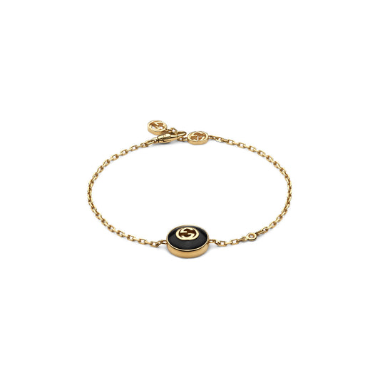 The Gucci Interlocking G 18K Yellow Gold Chain Bracelet With Onyx from GUCCI Fine Jewellery showcases a circular black onyx charm adorned with a gold emblem, complemented by an Interlocking G emblem near the clasp. This sleek and elegant design exudes sophistication.