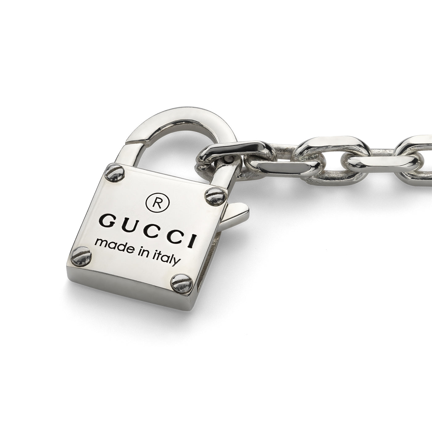 The Gucci Trademark Sterling Silver Chain Bracelet With Padlock from GUCCI Fine Jewellery features a sleek and polished sterling silver padlock adorned with the iconic Gucci Trademark and "GUCCI made in Italy" text, which is attached to a thick metallic chain, embodying the brand's luxury aesthetic.