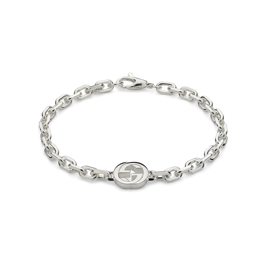 The Gucci Interlocking G Sterling Silver Bracelet by GUCCI Fine Jewellery is crafted in 925 sterling silver, featuring chain links with a circular emblem and interlocking G charm at the center, complete with a clasp fastening.