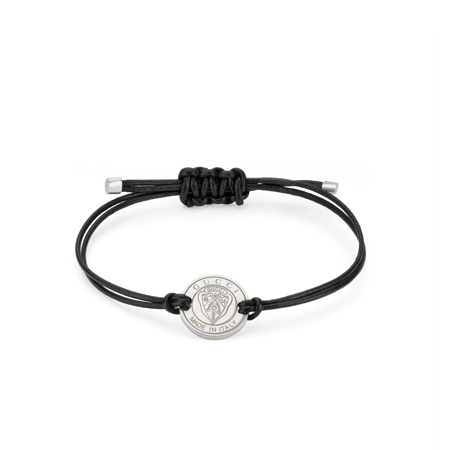 The Gucci Crest Leather Cord with Sterling Silver Bracelet by GUCCI Fine Jewellery features a minimalist black leather cord, an adjustable knot, and a sterling silver charm engraved with "GUCCI" and "MADE IN ITALY," showcasing the iconic lion head crest.