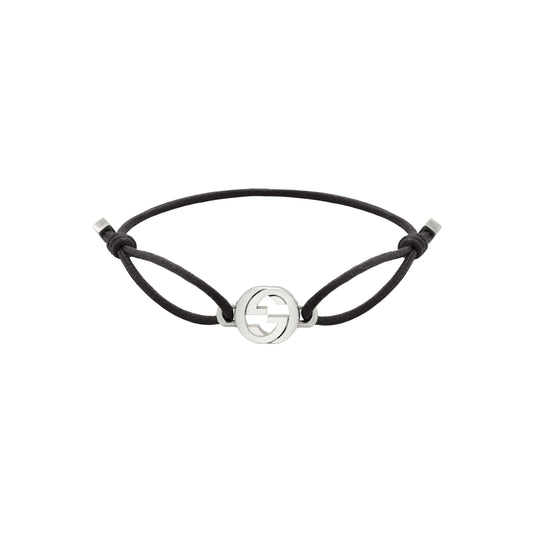 The Gucci Interlocking Cotton Cord with Sterling Silver Bracelet by GUCCI Fine Jewellery features a minimalist black cord, an interlocking G sterling silver emblem, adjustable knotted closure, and elegant silver end caps.