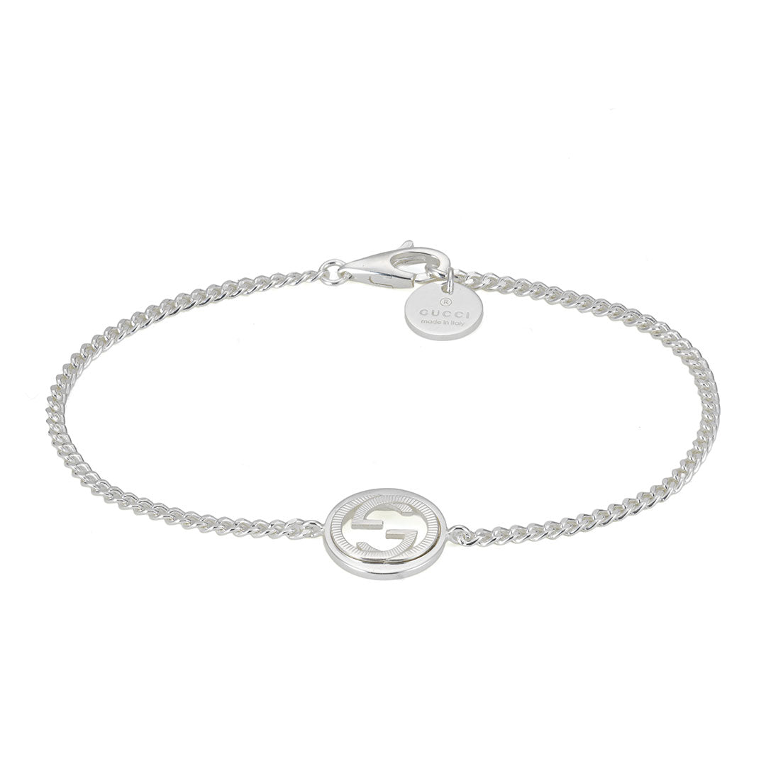 The Gucci Interlocking G Sterling Silver Charm Bracelet by GUCCI Fine Jewellery features a slender sterling silver chain adorned with the signature Interlocking G logo in a refined guilloché cut-out at its center, as well as a small round tag near the lobster clasp—an elegant choice for those who appreciate fine sterling silver accessories.