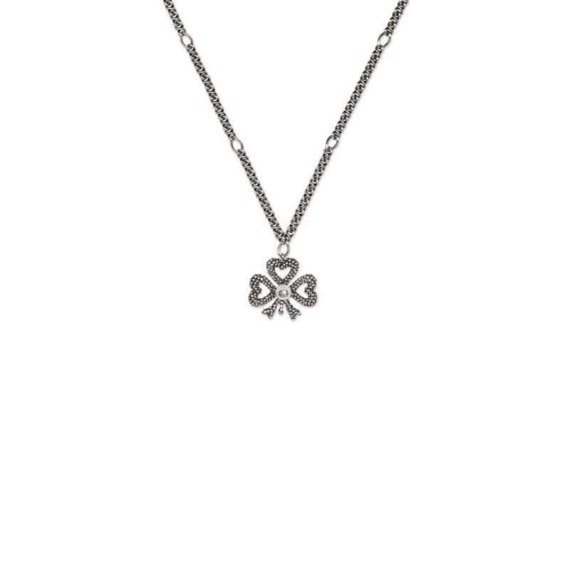 The Gucci Clover Sterling Silver Necklace Pendant from GUCCI Fine Jewellery showcases a clover-shaped pendant embellished with small stones. The design features three heart-shaped leaves, while the chain, highlighted by circular links, reflects Gucci's iconic elegance against a plain white background.