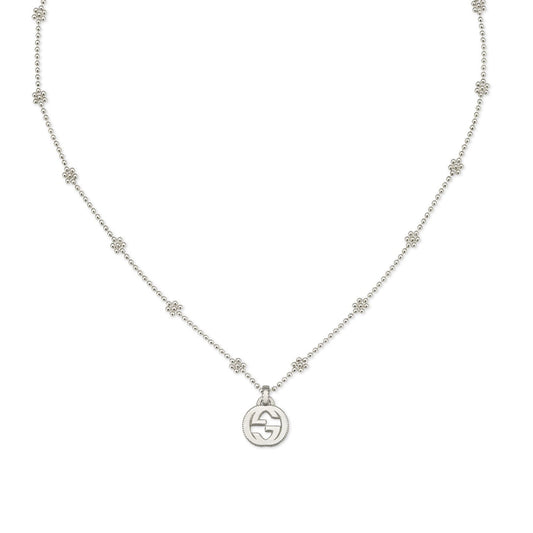 The GUCCI Fine Jewellery piece is a Gucci Interlocking G Sterling Silver Necklace Pendant, showcasing a sequence of small, evenly spaced decorative links. The circular pendant highlights intricate flower motifs at its center, with the chain elegantly forming a full circle against a white background.